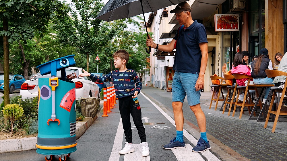 Kind und Mann im Stadtraum an einer Straße mit Bäumen